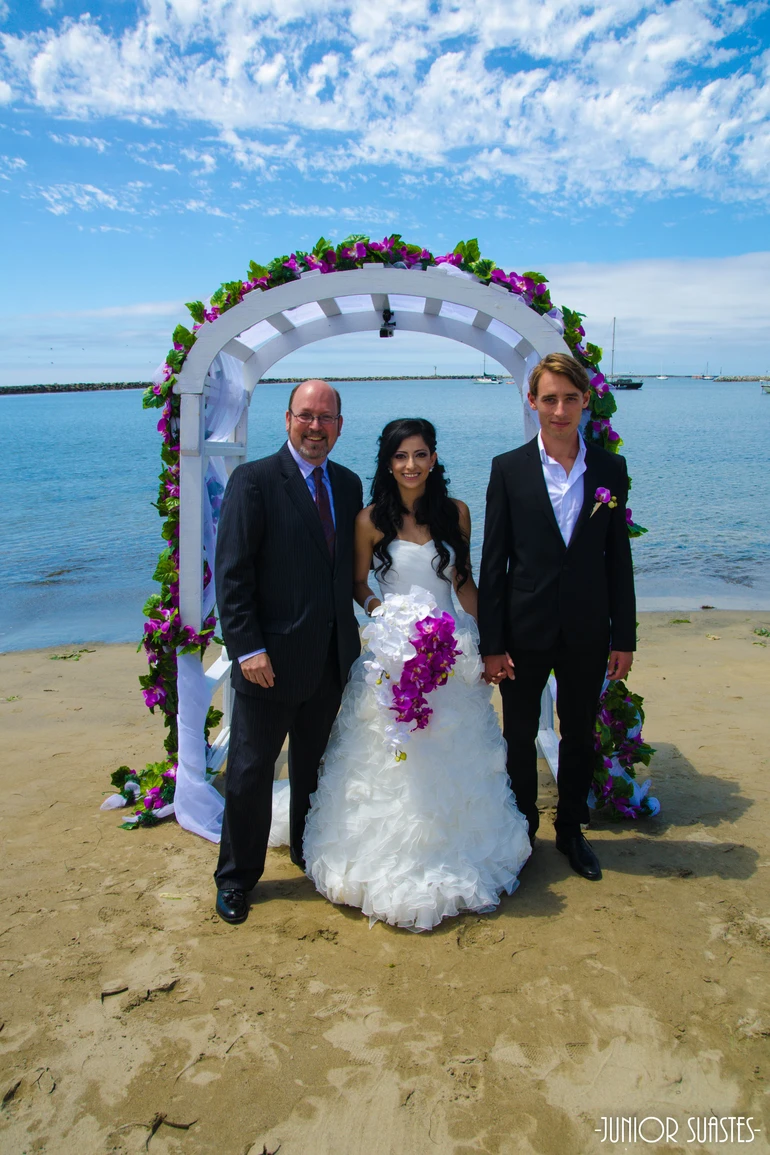 Howard with Bride and Groom at the beach under arch